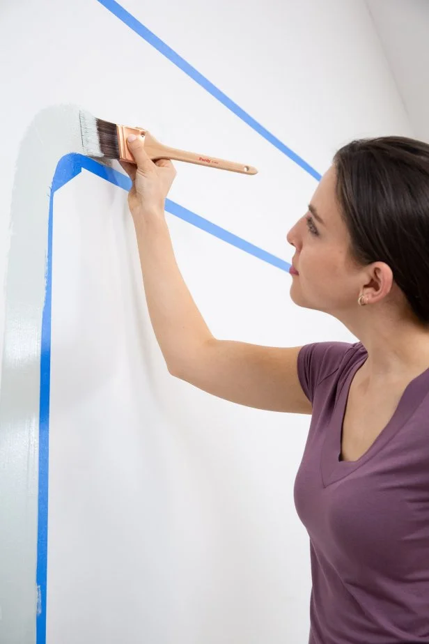 The next step in this bold bar DIY is to paint the first and lighter of the two complementary colors on the wall.
